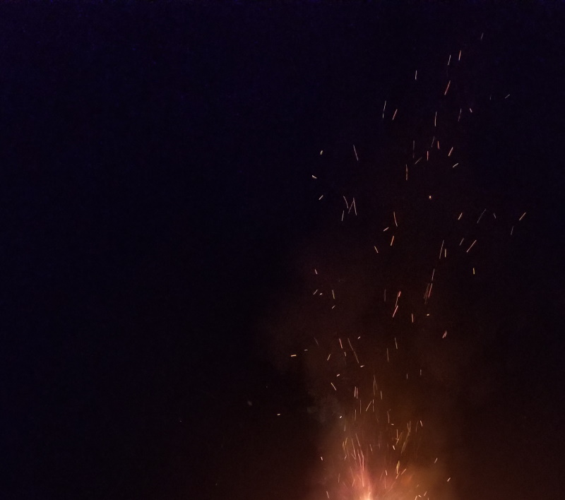 Photo of embers flying into the night sky from a campfire.